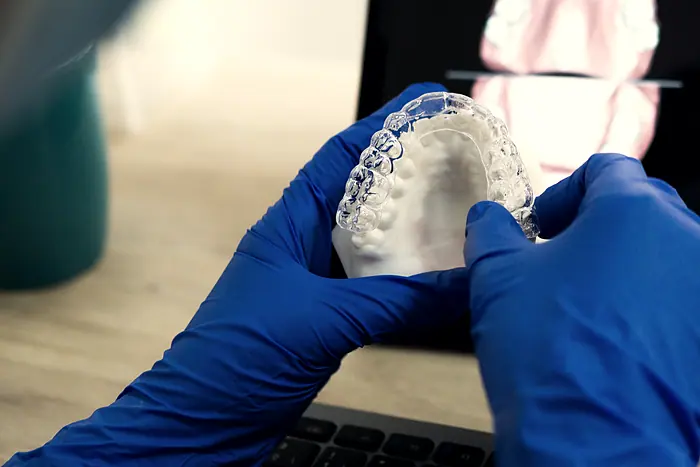 A technician checking a finished aligner against the printed model